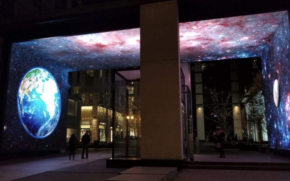 Three-sided LED screens at a building entrance at night