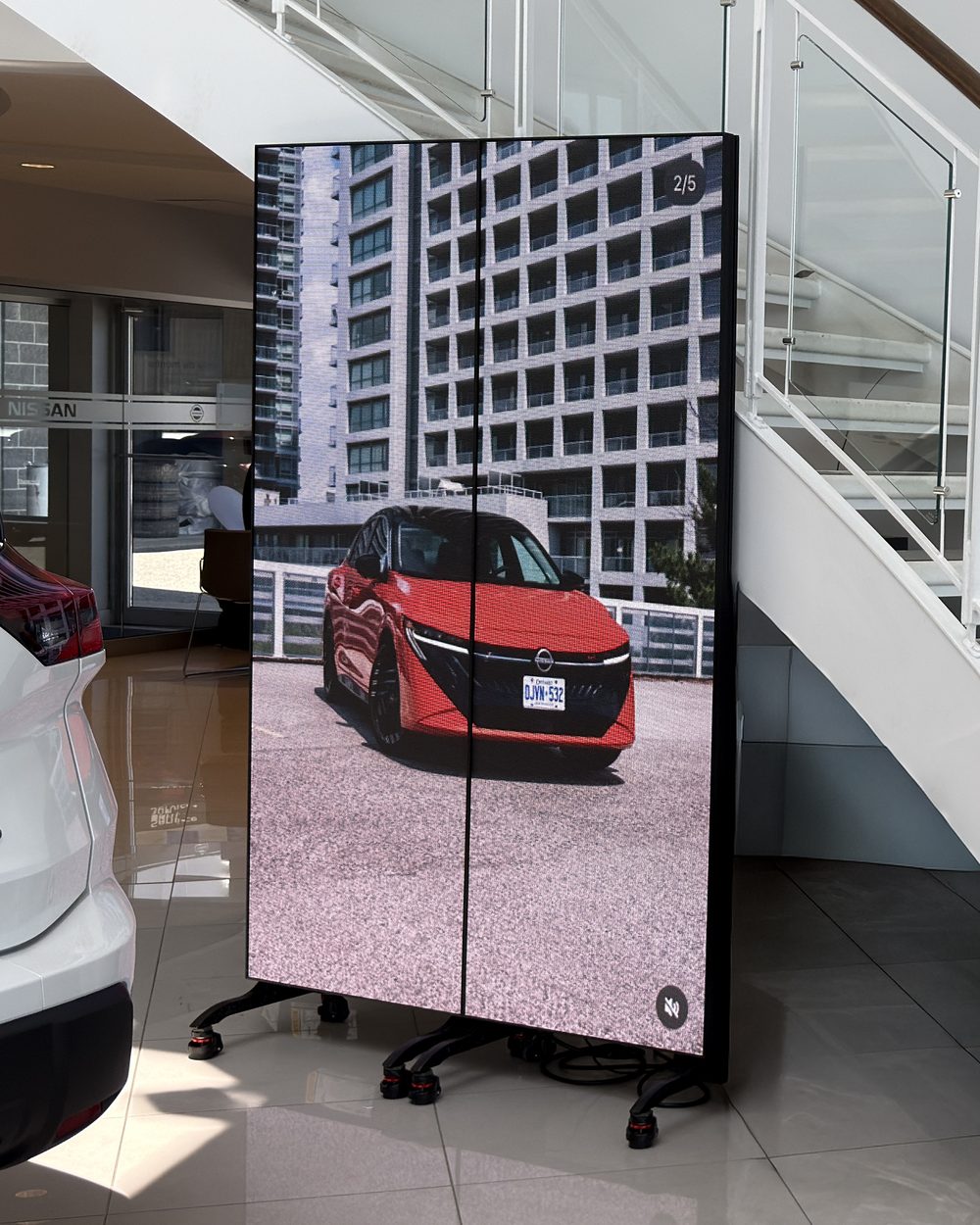 Two Interior Poster LED displays on wheeled stands in a Nissan dealership showroom