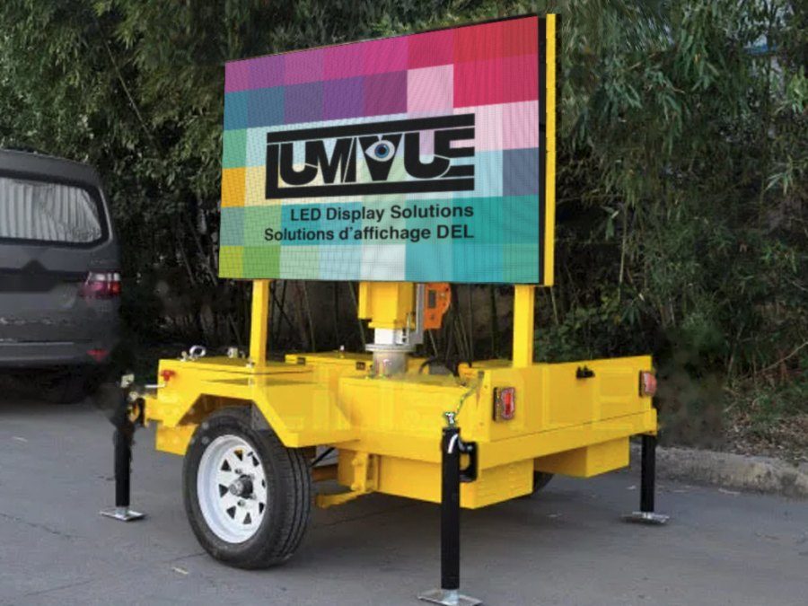Remorque jaune avec un grand écran DEL horizontal, stationnée sur un terrain